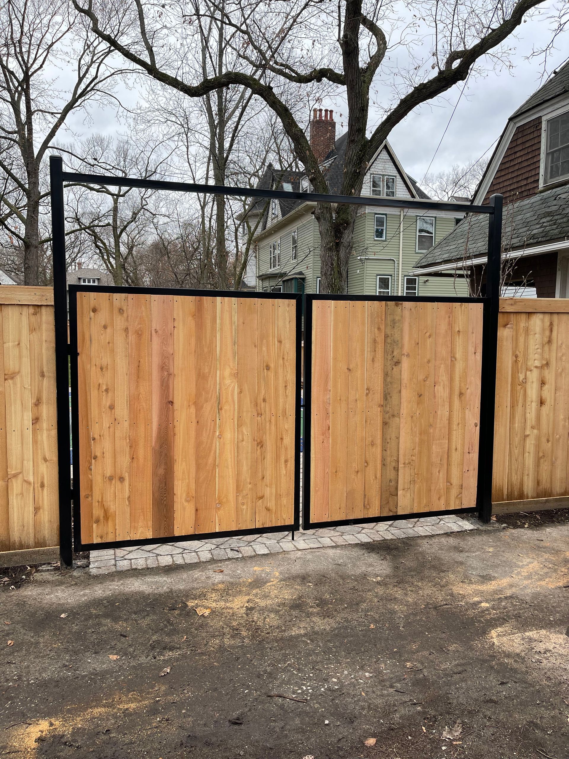 A wooden gate with a metal frame is sitting in front of a house.