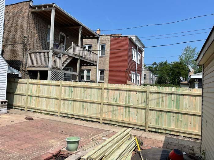 A wooden fence is being built in the backyard of a house.