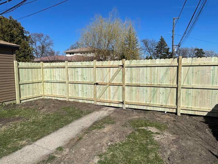 A wooden fence with a gate in the backyard of a house.