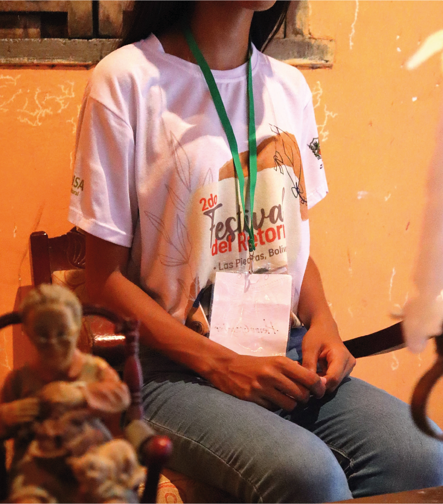 Una mujer que lleva una camiseta de festival está sentada en una silla.
