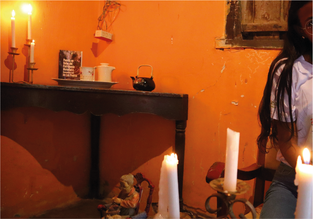 Una mujer está sentada frente a una mesa con velas.