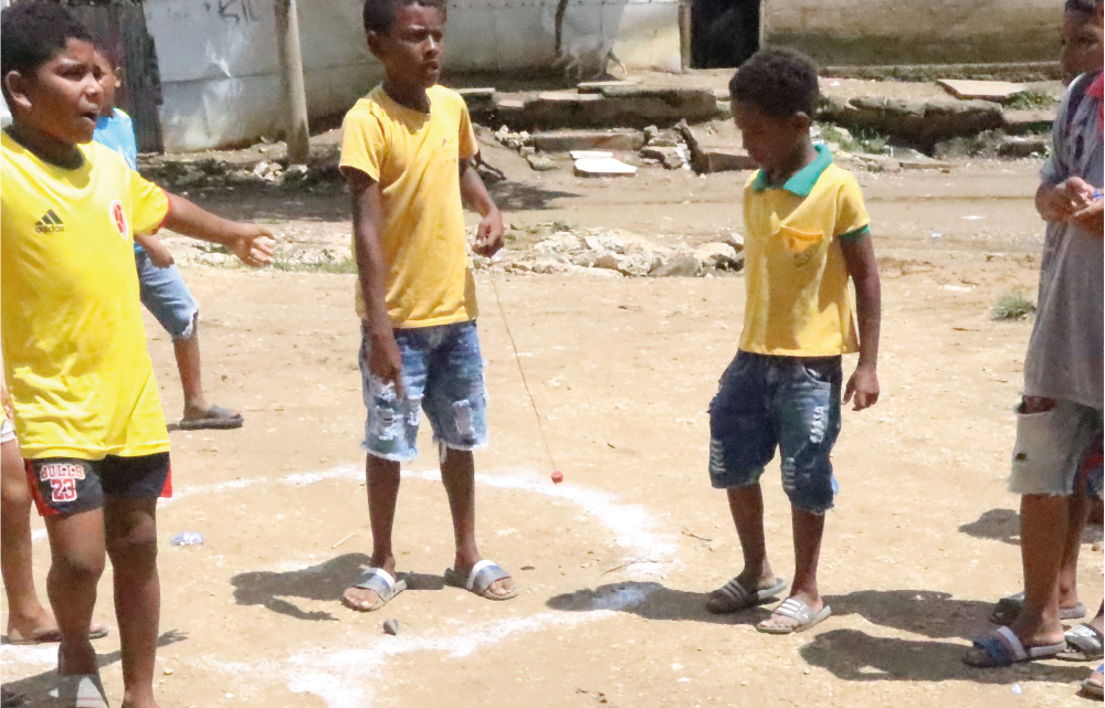 Un grupo de niños está jugando en un campo de tierra.
