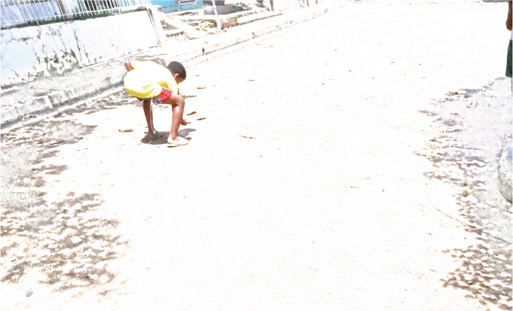 Un niño pequeño está haciendo una parada de manos en un camino de tierra.