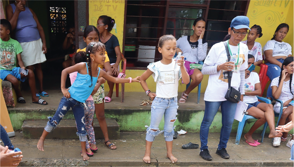 Un grupo de niños está bailando delante de una multitud de personas.
