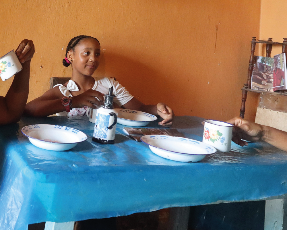 Una niña se sienta a una mesa con cuencos y tazas.