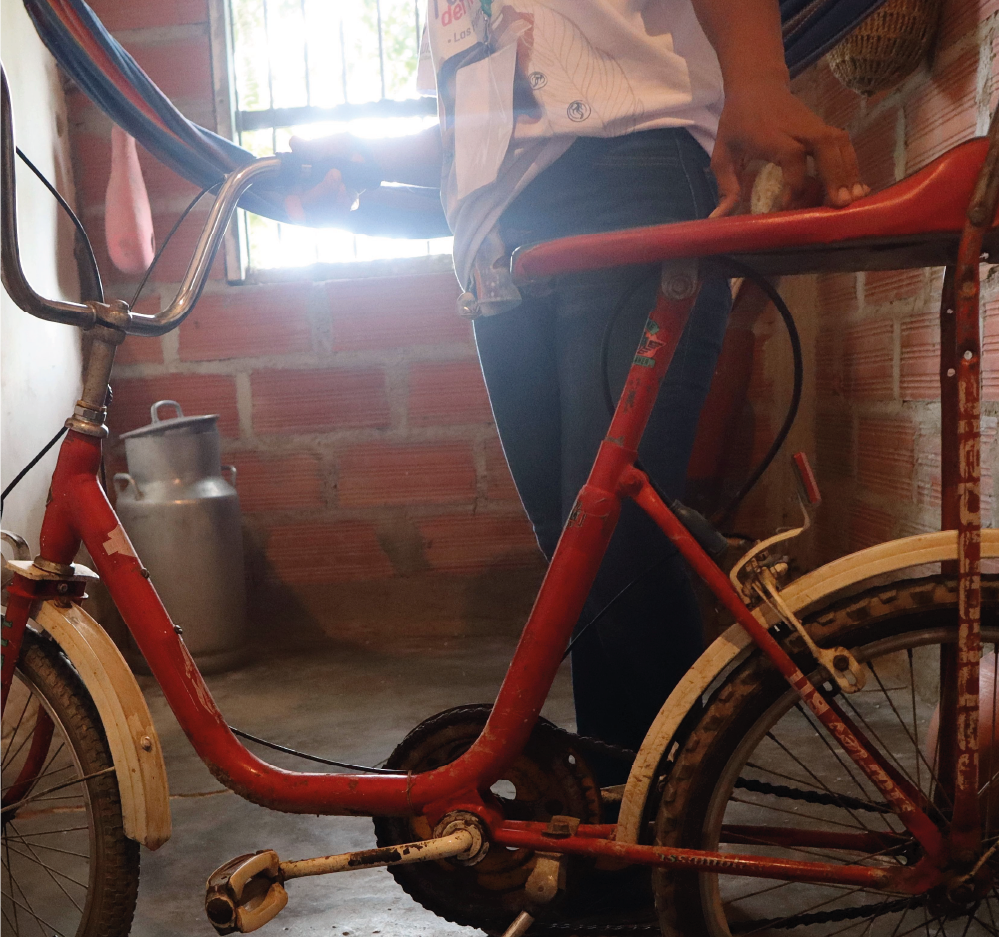 Una persona está parada junto a una bicicleta roja con un guardabarros blanco.