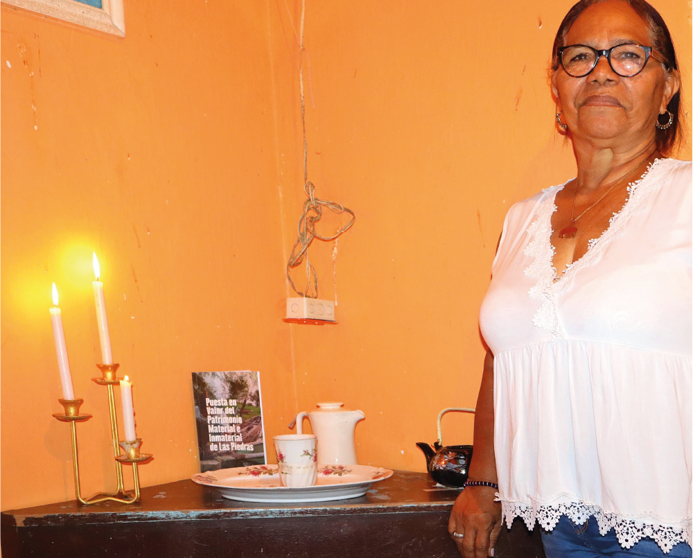Una mujer está parada frente a una mesa con velas y un libro sobre ella.