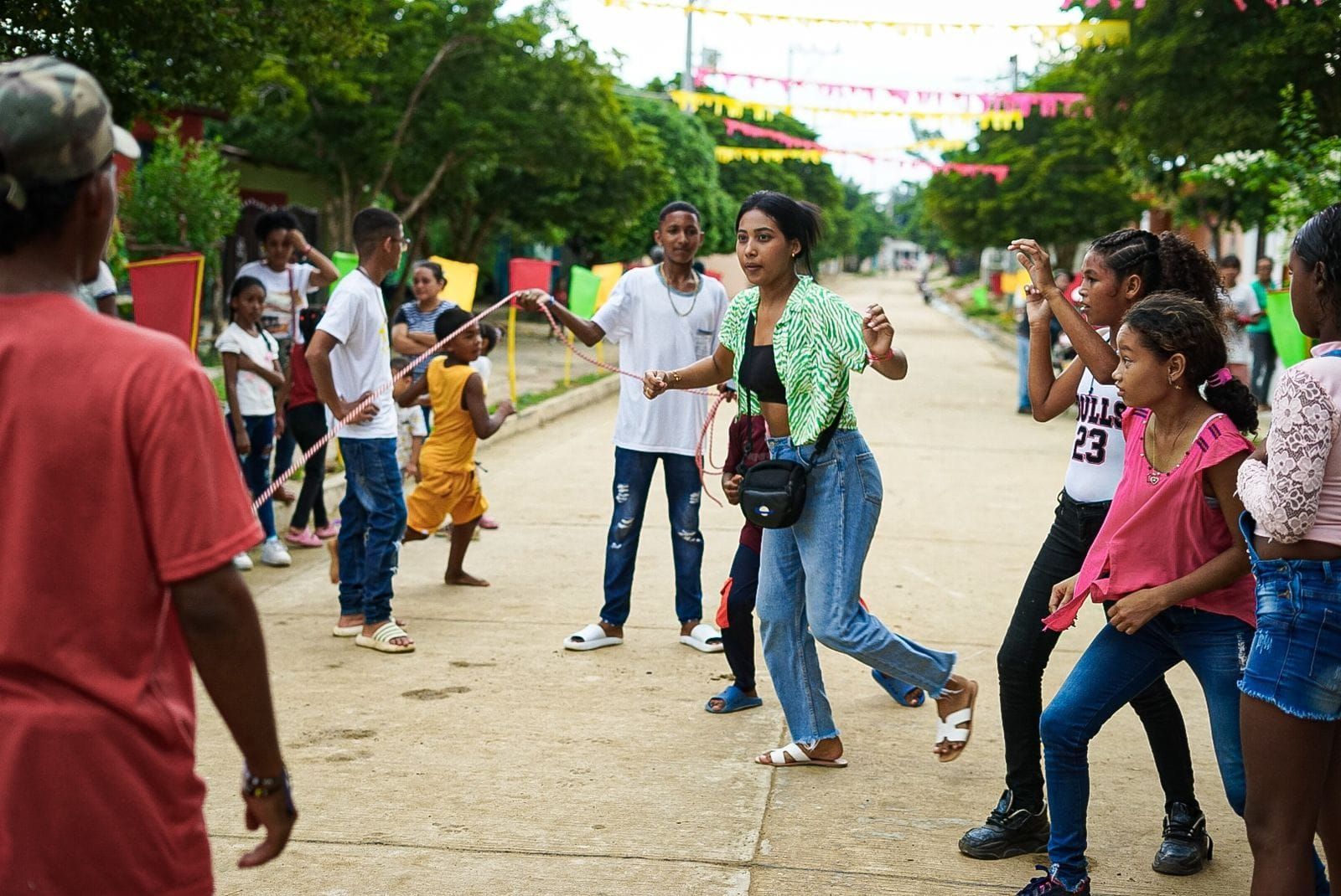 Gente jugando en la calle, con adornos festivos. Mujeres jóvenes y niños ríen y se mueven.