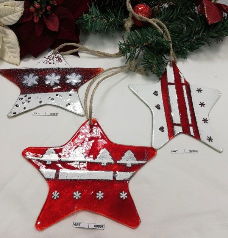 Tre decorazioni natalizie in vetro a forma di stella, di colore rosso e bianco, con vari motivi natalizi, appese con uno spago.