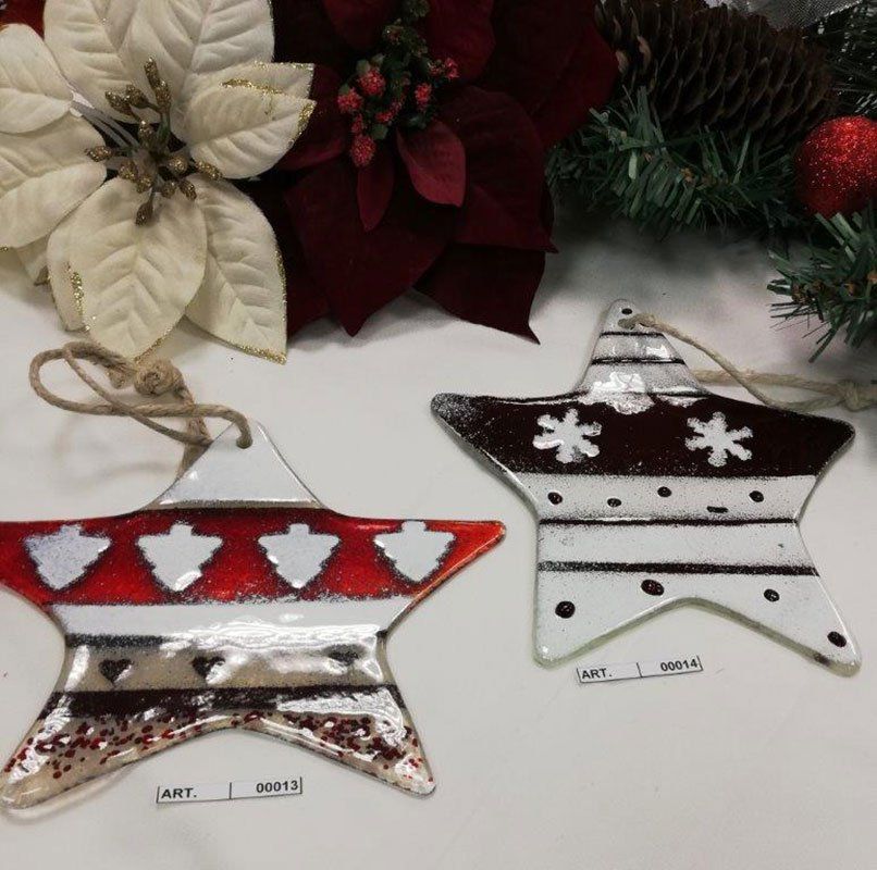 Due decorazioni natalizie a forma di stella con motivi rossi, bianchi e marroni; sullo sfondo decorazioni natalizie.