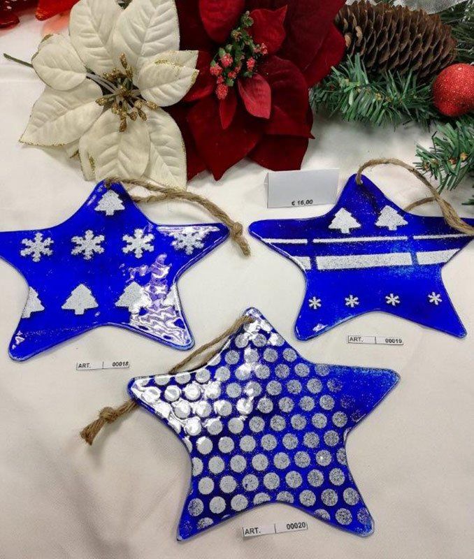 Tre decorazioni natalizie a forma di stella blu con motivi bianchi: fiocchi di neve, alberi e pois. Appendiabiti in corda.