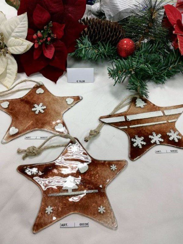 Tre decorazioni natalizie marroni a forma di stella con dettagli bianchi e anelli di spago per appenderle, esposte insieme alle decorazioni natalizie.