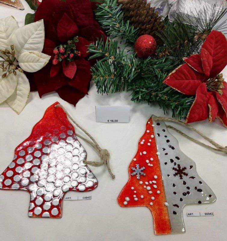 Due decorazioni natalizie in vetro, rosse e argentate, con decorazioni rosse e bianche, su un tavolo con decorazioni natalizie.