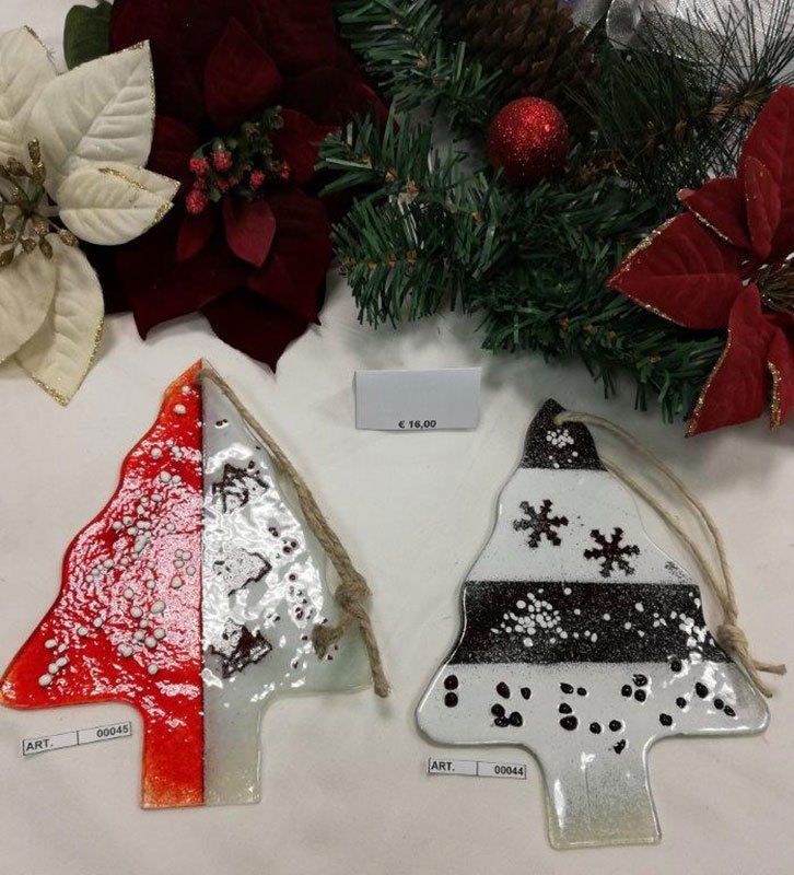 Due decorazioni natalizie in vetro, rosse e bianche, con verde natalizio e stelle di Natale sullo sfondo.