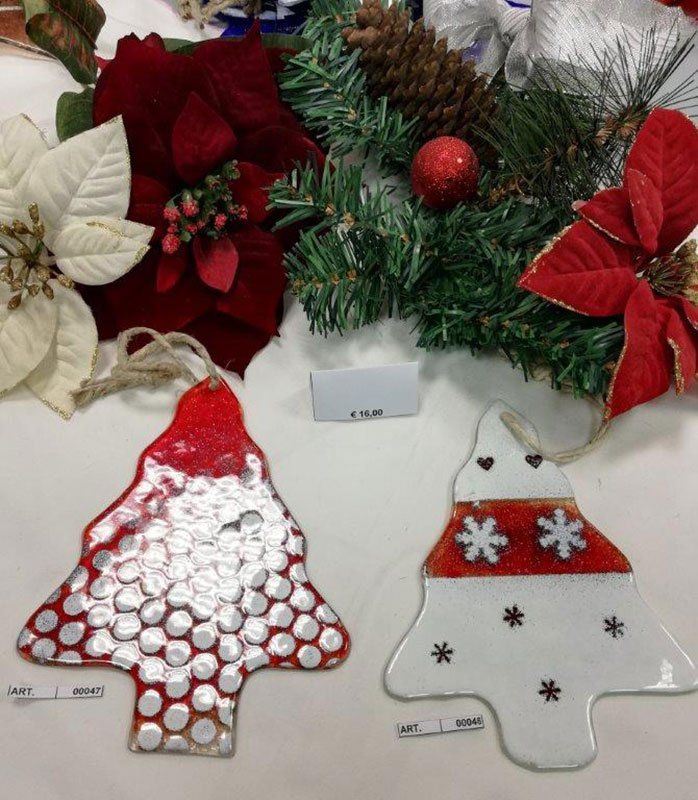 Due decorazioni natalizie in vetro con motivi rossi e bianchi, circondate da decorazioni festive.