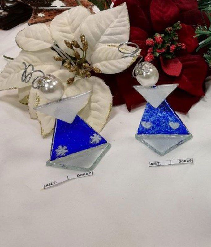 Due ornamenti a forma di angelo blu e argento, vicino a una stella di Natale bianca e fiori rossi.