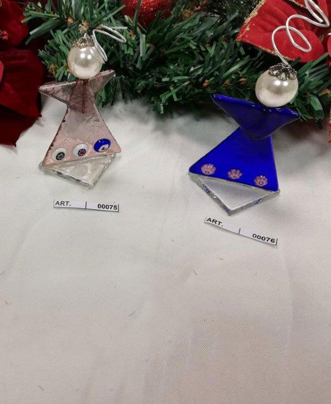 Due ornamenti in vetro a forma di angelo con teste di perle e ali blu e rosa, esposti con verde natalizio.