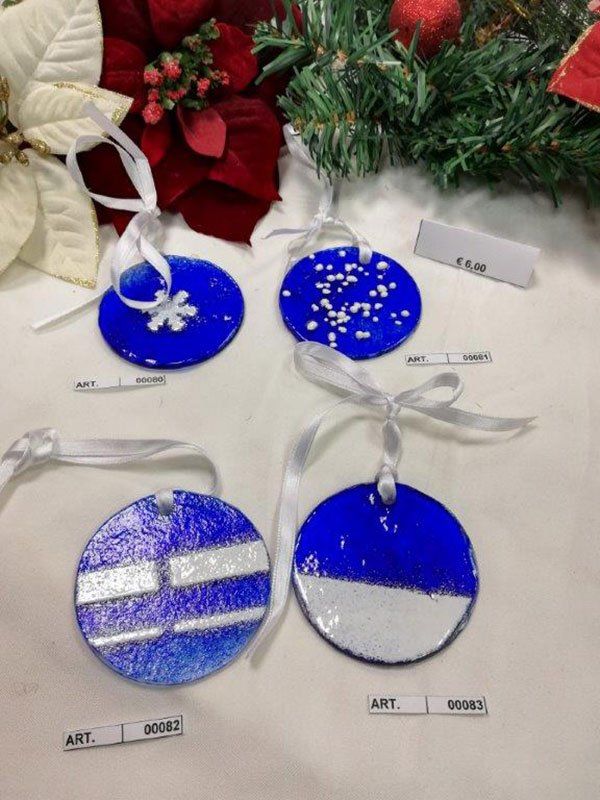 Quattro decorazioni natalizie rotonde, blu e bianche, con nastri, esposte insieme a festive stelle di Natale.