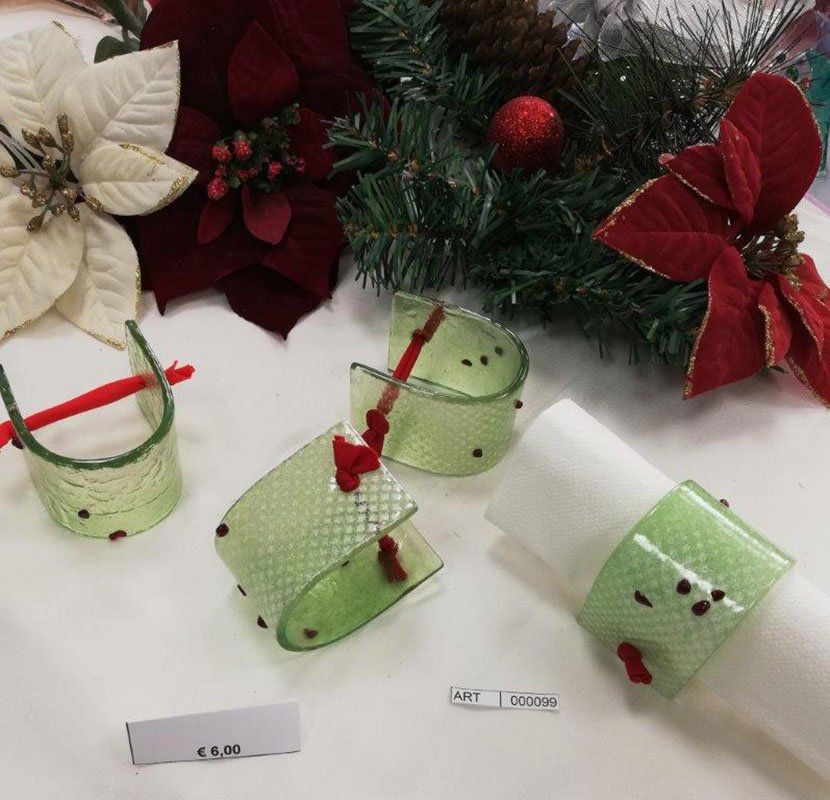 Portatovaglioli natalizi verdi e rossi con stelle di Natale bianche e rosse e rami sempreverdi.