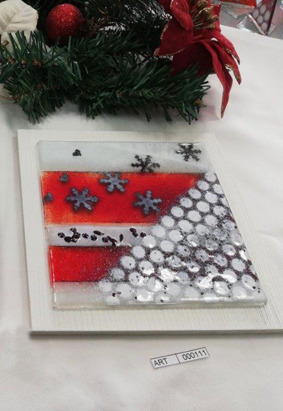 Decorazione in vetro a tema natalizio con strisce rosse e fiocchi di neve. Presenta una ghirlanda bianca, argento e verde.