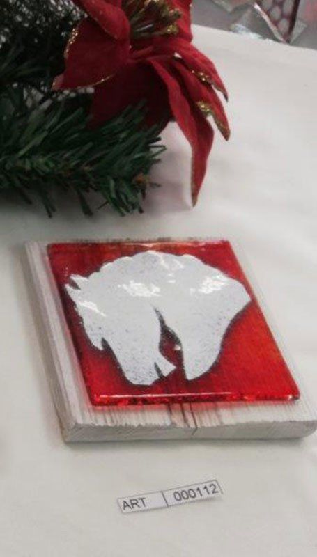 Opera in vetro con forme bianche su sfondo rosso, montata su legno; stella di Natale sullo sfondo.