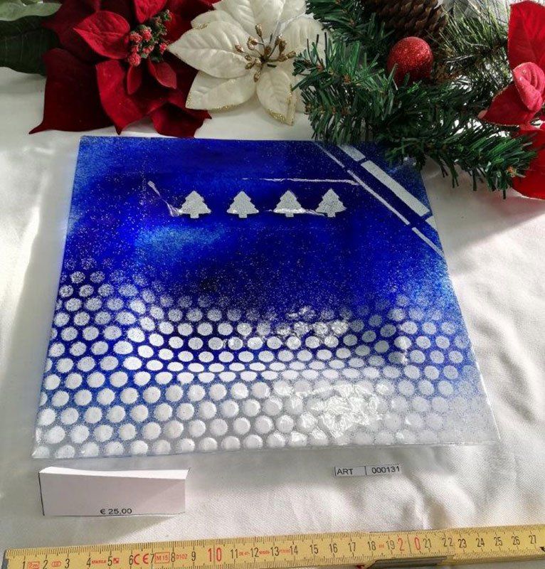 Opera d'arte in vetro quadrato blu e bianco con alberi e motivo a nido d'ape, decorazioni natalizie sullo sfondo.