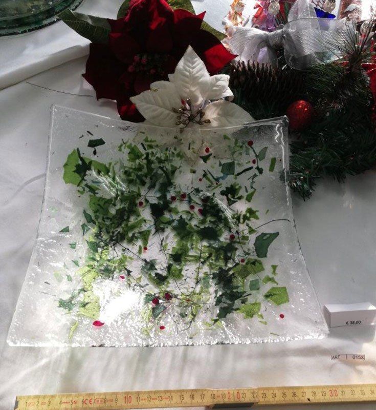 Piatto quadrato in vetro con dettagli verdi e rossi, vicino a decorazioni natalizie e un righello.