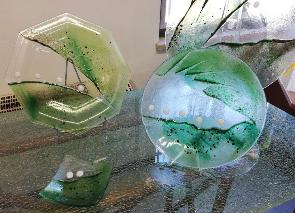 Arte del vetro: pezzi a forma di esagono, cerchio e foglia, con accenti verdi e bianchi.