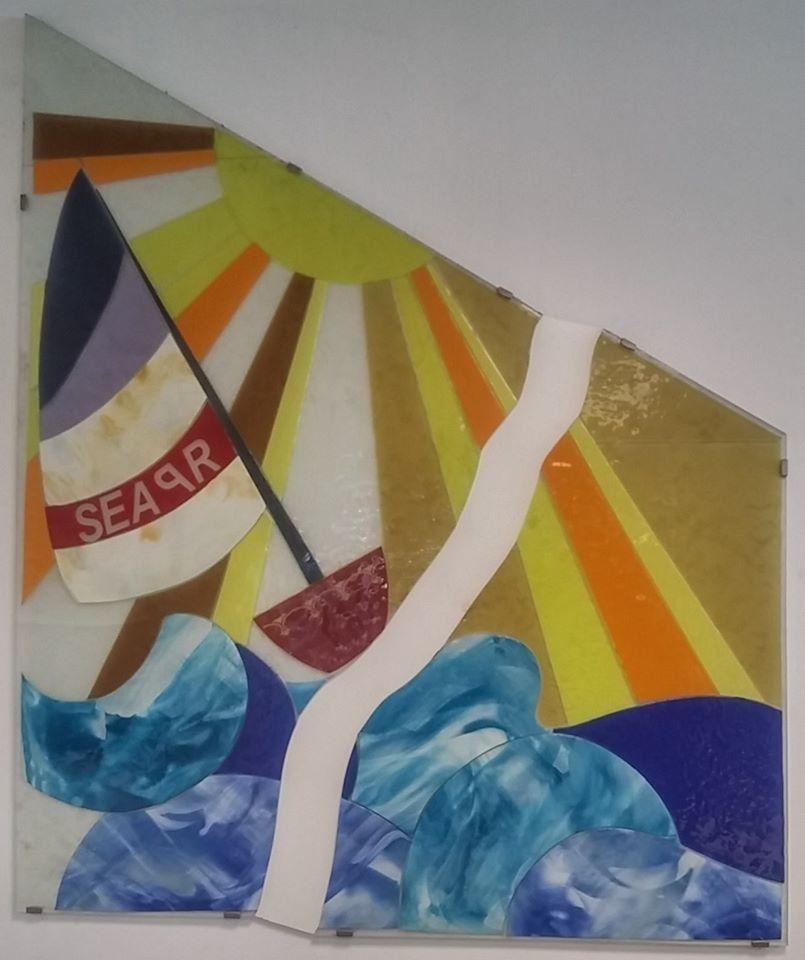 Vetrata artistica: barca a vela sulle onde, sfondo a raggi di sole. 