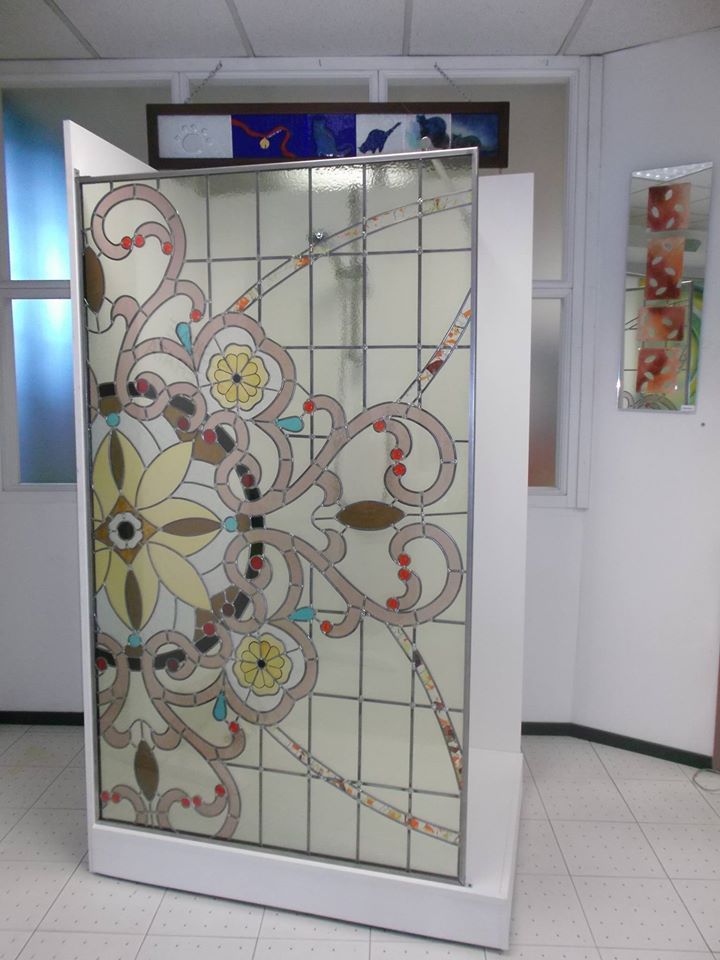 Pannello in vetro colorato con cornice bianca, caratterizzato da motivi floreali e astratti nelle tonalità del beige, del giallo e del marrone.