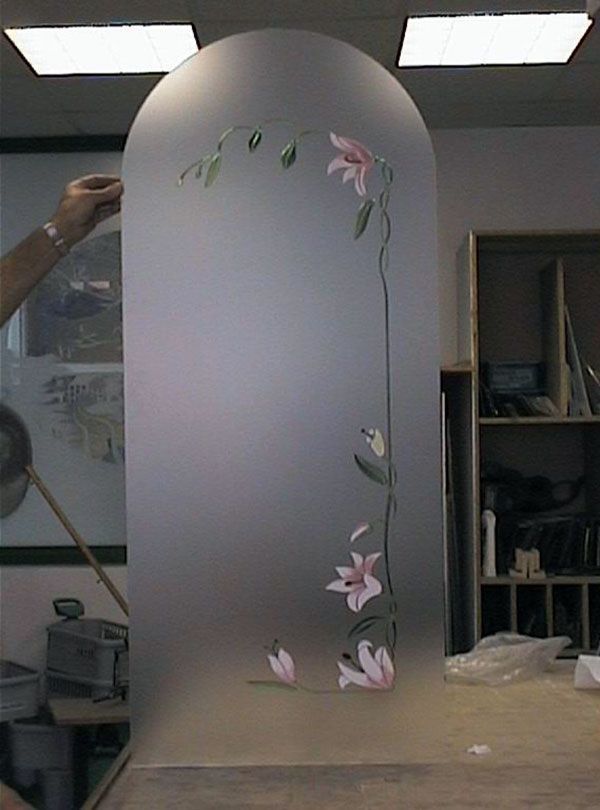 Pannello in vetro smerigliato con parte superiore ad arco, motivo floreale dipinto, tenuto da una persona in un laboratorio.