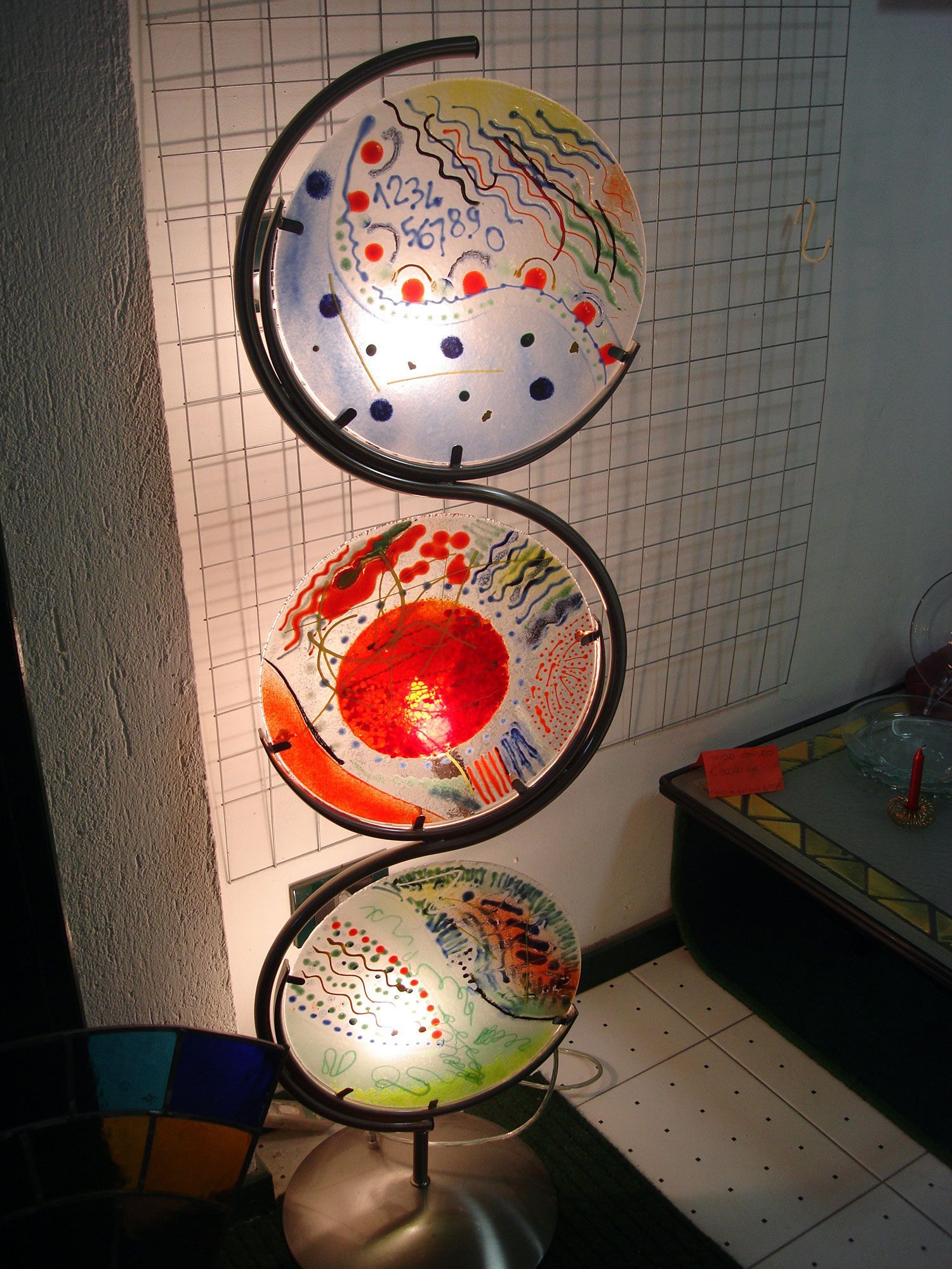 Lampada da terra astratta con tre paralumi circolari in vetro colorato.