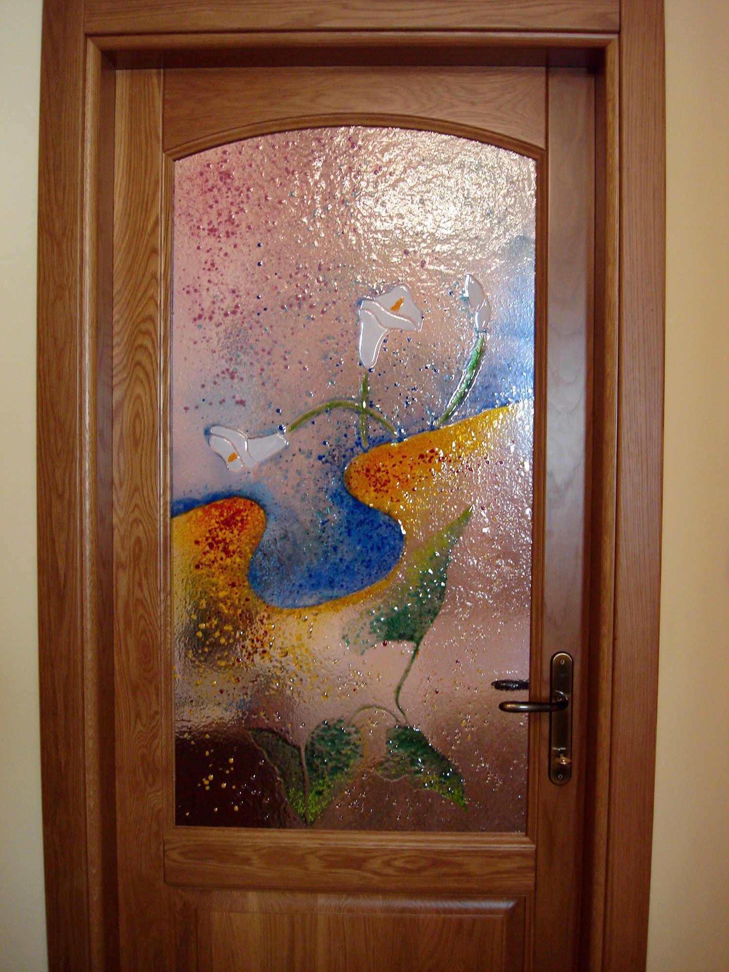 Porta in legno con pannello in vetro colorato con motivo floreale astratto nei colori blu, giallo e rosa.