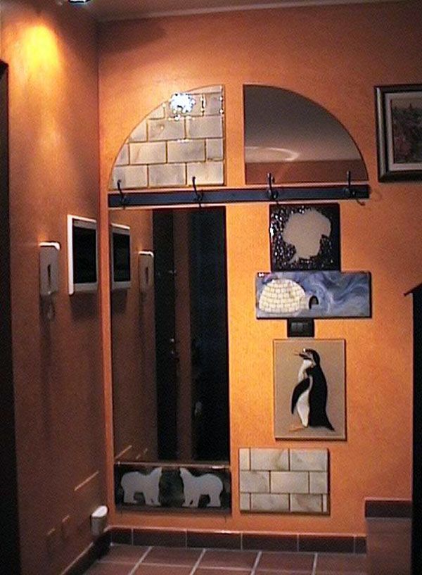 Ingresso con pareti arancioni, grande specchio, opere d'arte decorative e dipinto di un pinguino.