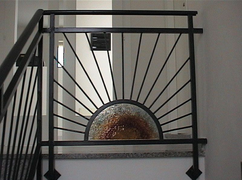 Ringhiera per scale in metallo nero con motivo a raggiera e pannello in vetro.