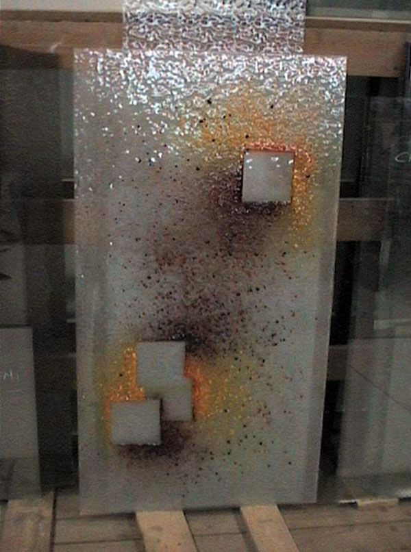 Opera d'arte in vetro testurizzato con sfumature di colore screziate e tre ritagli quadrati.