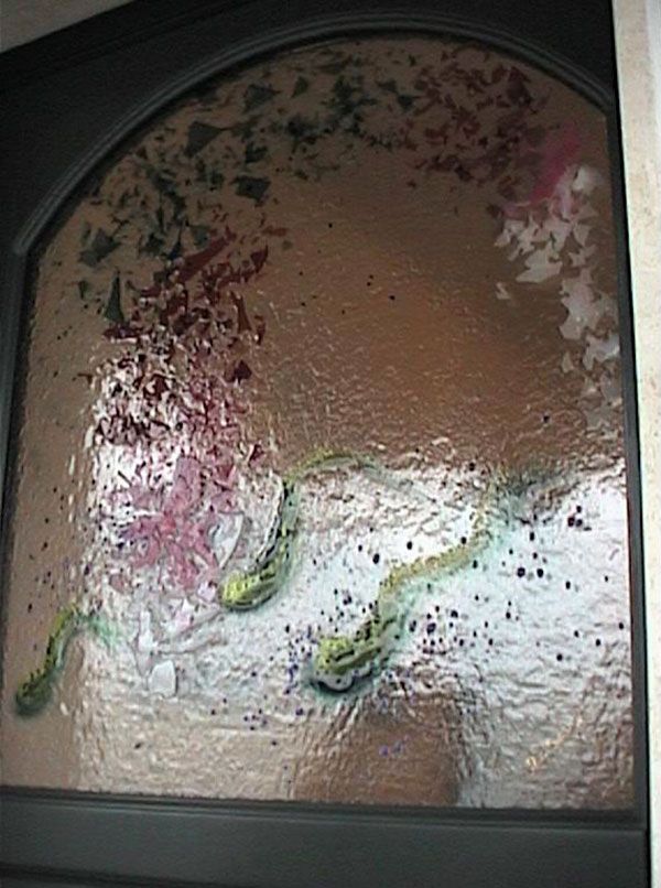 Porta in vetro ad arco con motivo floreale dipinto di rosa, verde e rosso e due pesci stilizzati verdi.