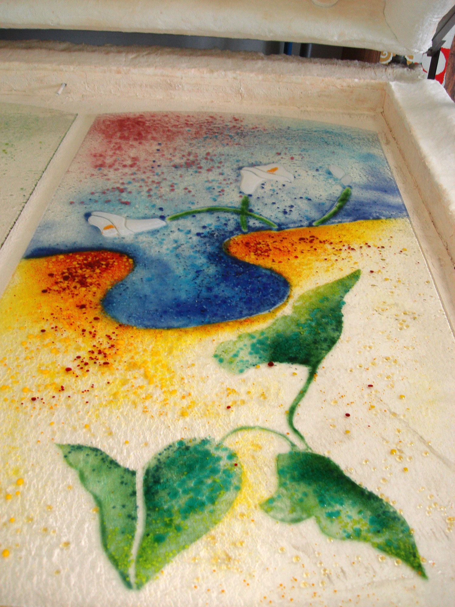 Arte astratta colorata: vaso blu, foglie verdi, sfondo giallo e rosso, su una superficie bianca.