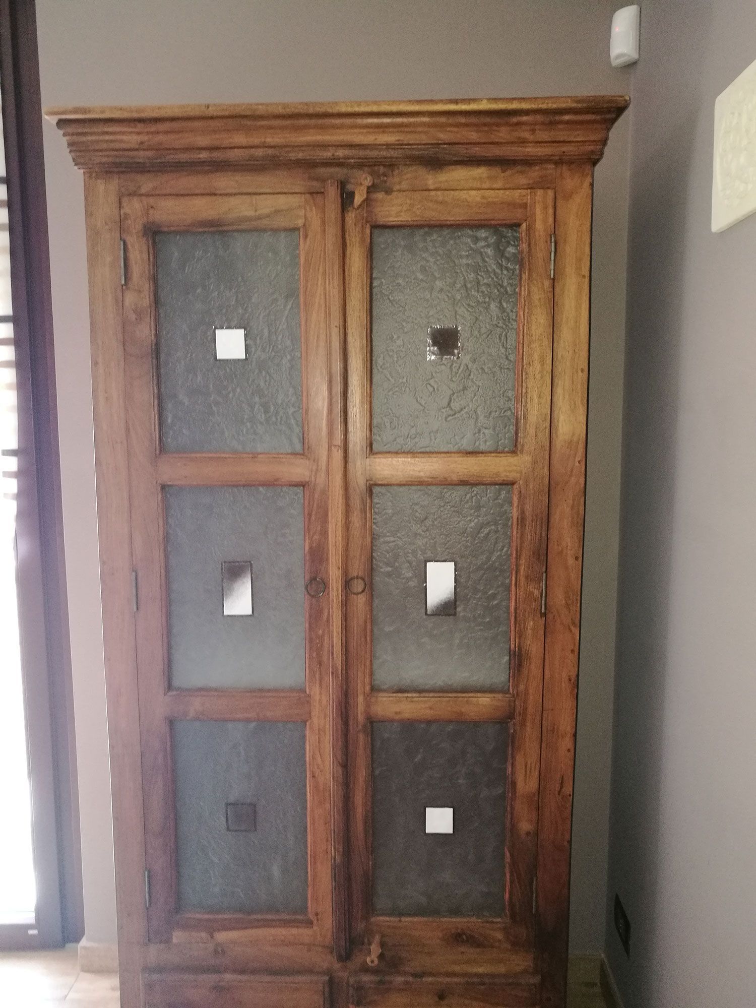 Mobiletto in legno con ante in vetro e dettagli quadrati.