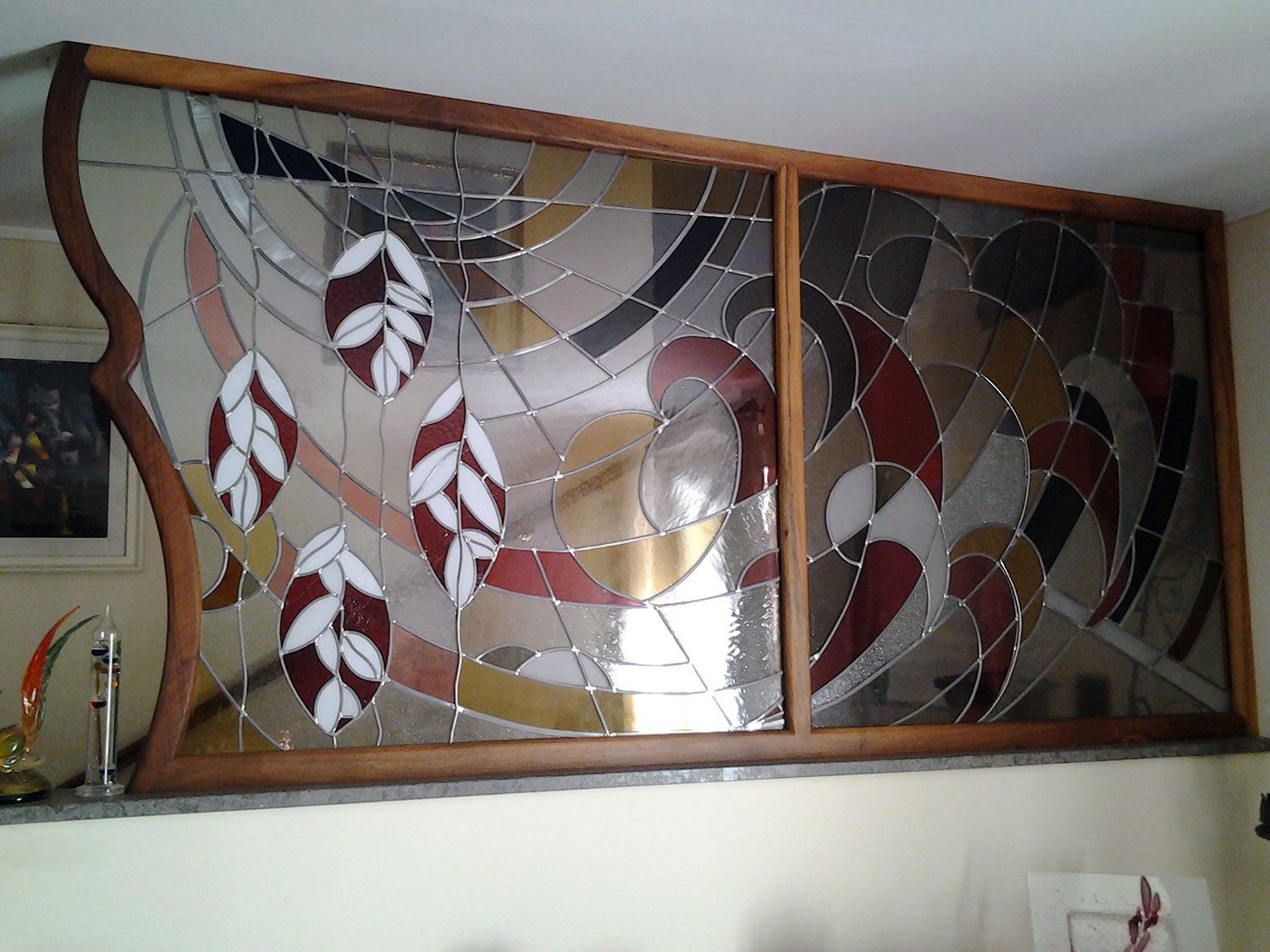 Vetrata con motivi fogliari e astratti in vari colori, incorniciata in legno.