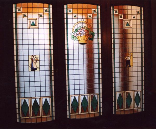 Tre pannelli di vetro colorato, ciascuno con figure e accenti verdi.