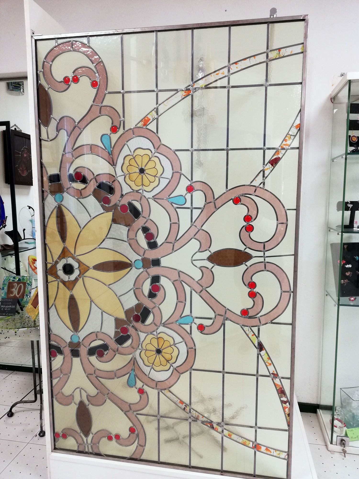 Pannello in vetro colorato con motivi floreali nei colori crema, rosa, giallo e marrone.