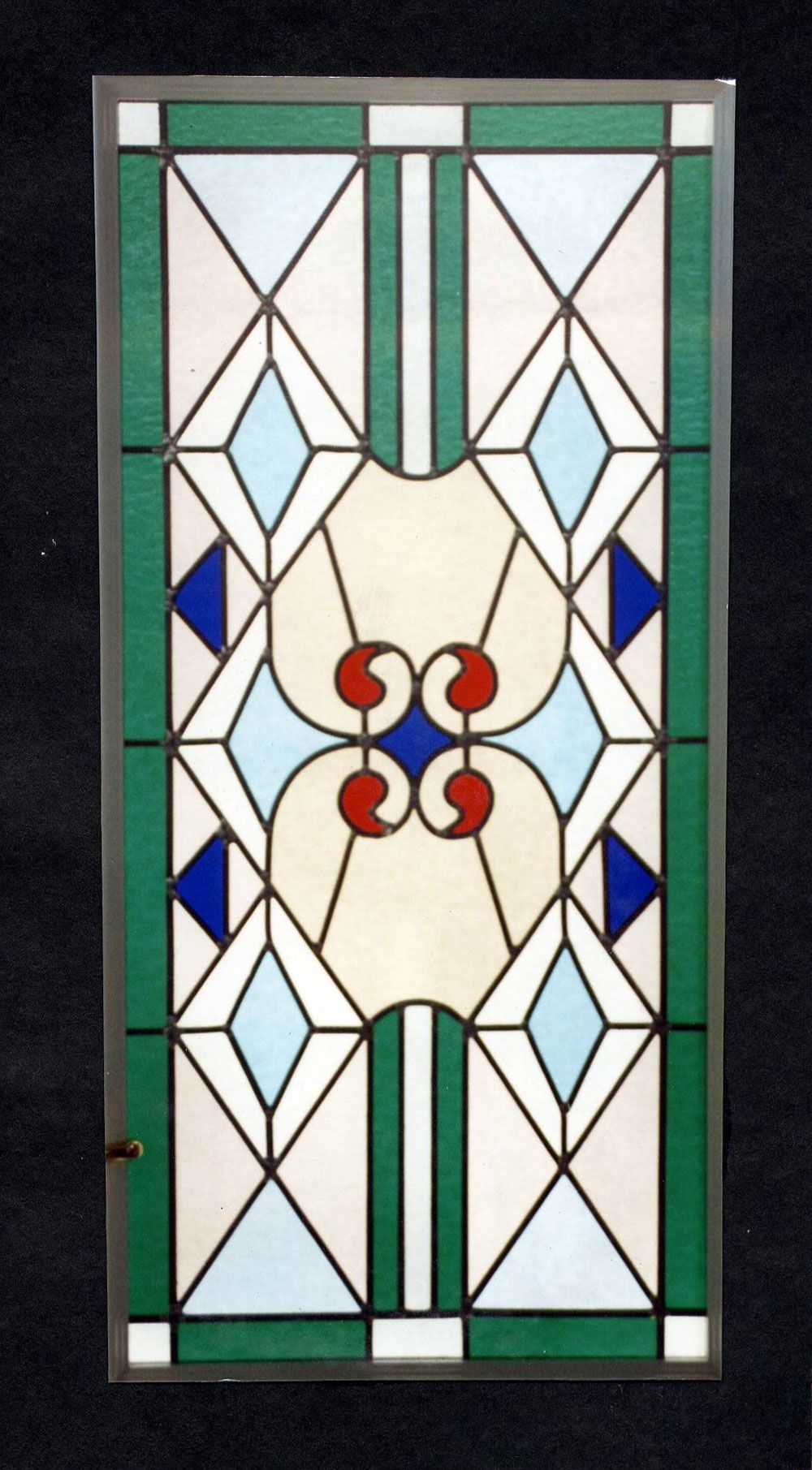 Pannello di vetro colorato con forme geometriche verdi, blu, bianche e rosse.