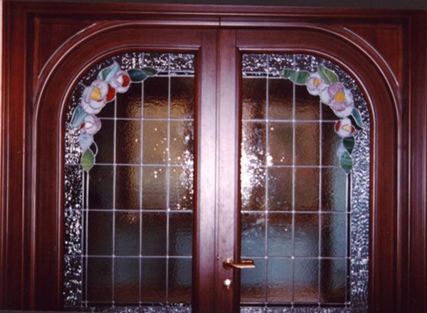 Doppie porte in legno con dettagli in vetro colorato con motivi floreali.