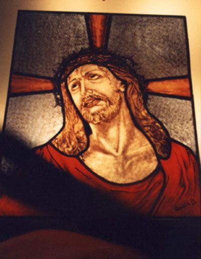 Gesù con una corona di spine e lo sguardo rivolto verso il basso. Veste rossa, croce sullo sfondo.