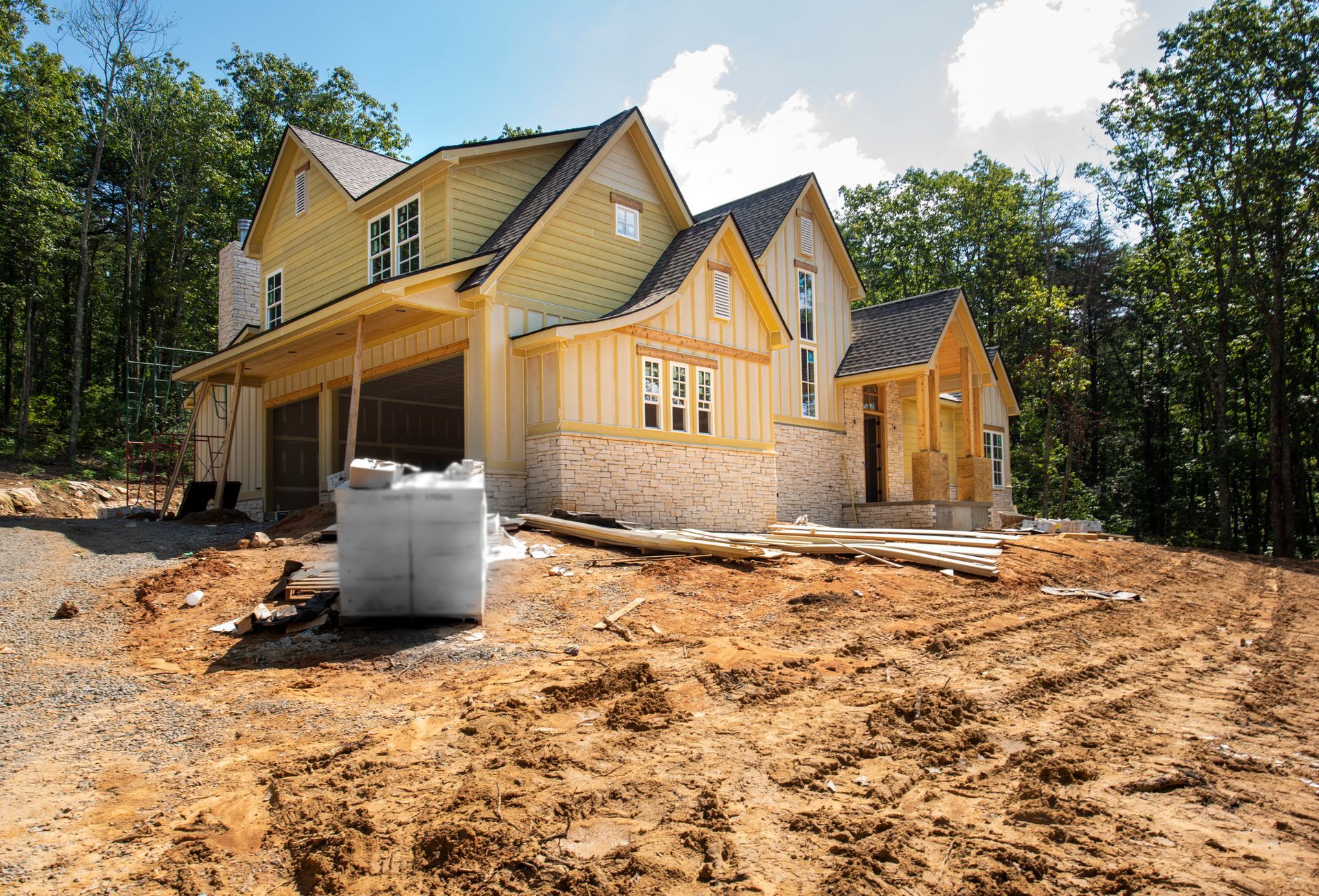 A large house is being built in the middle of a dirt field.
