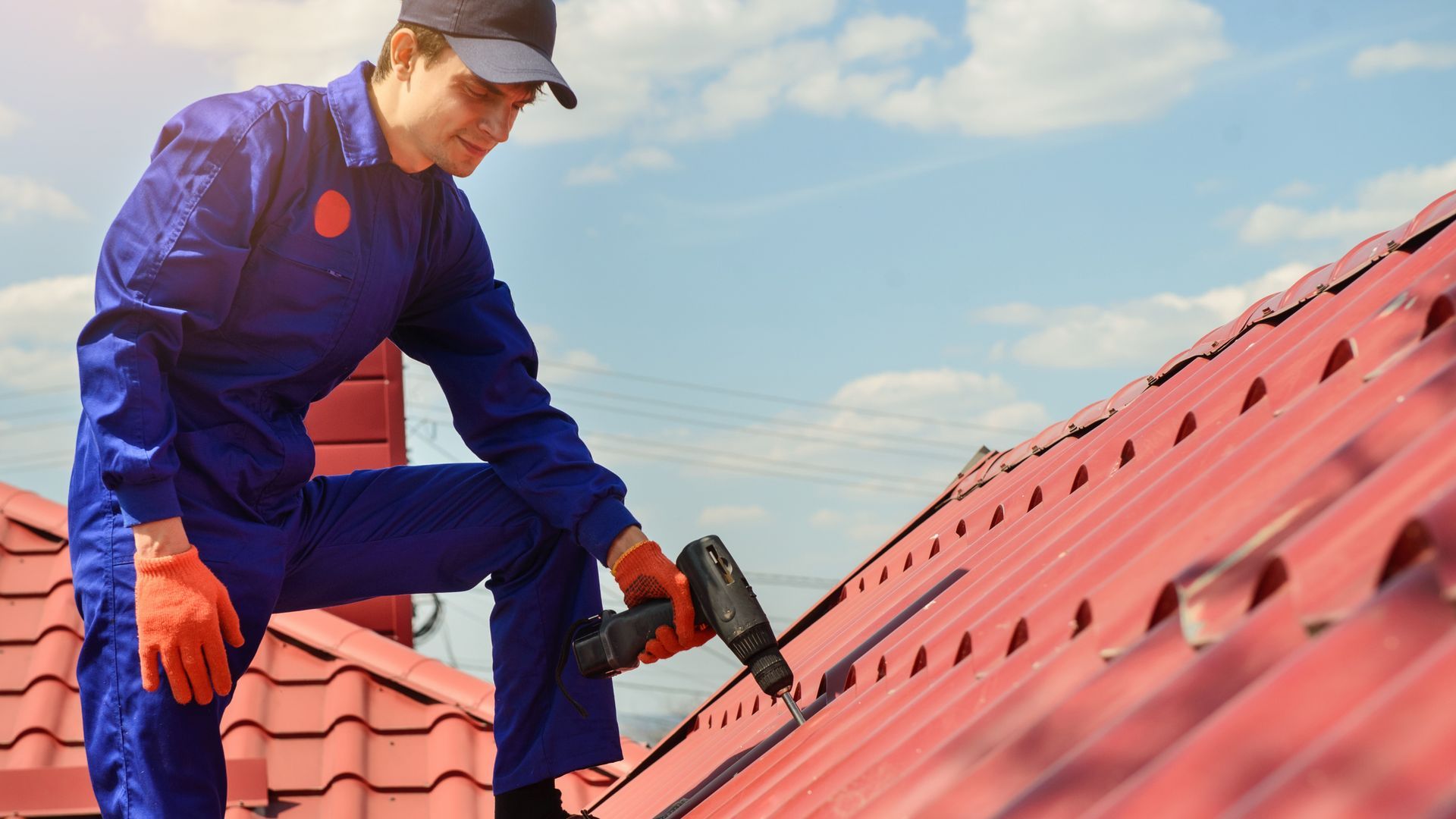 A man is working on a roof with a drill.