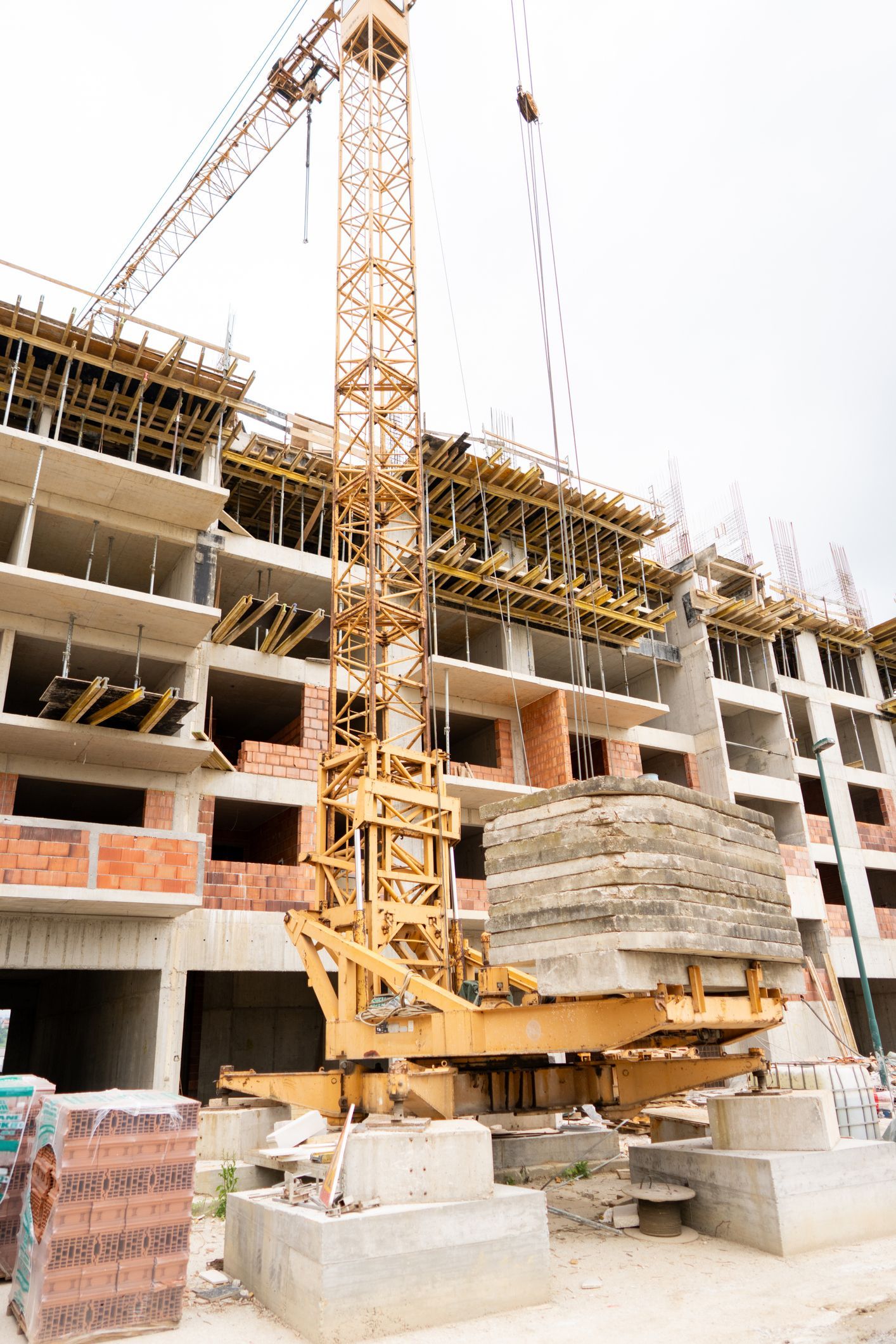 A construction site with a crane and bricks in front of a building under construction.