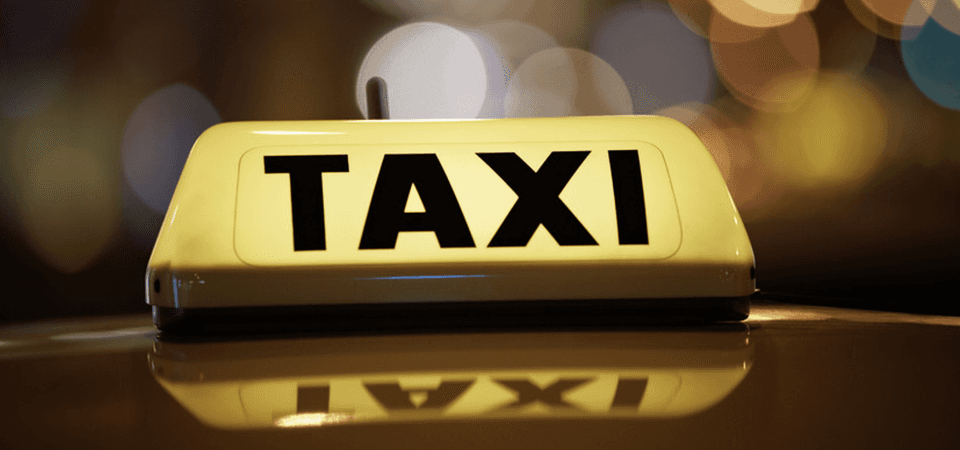 A yellow and black TAXI sign on the roof of a car