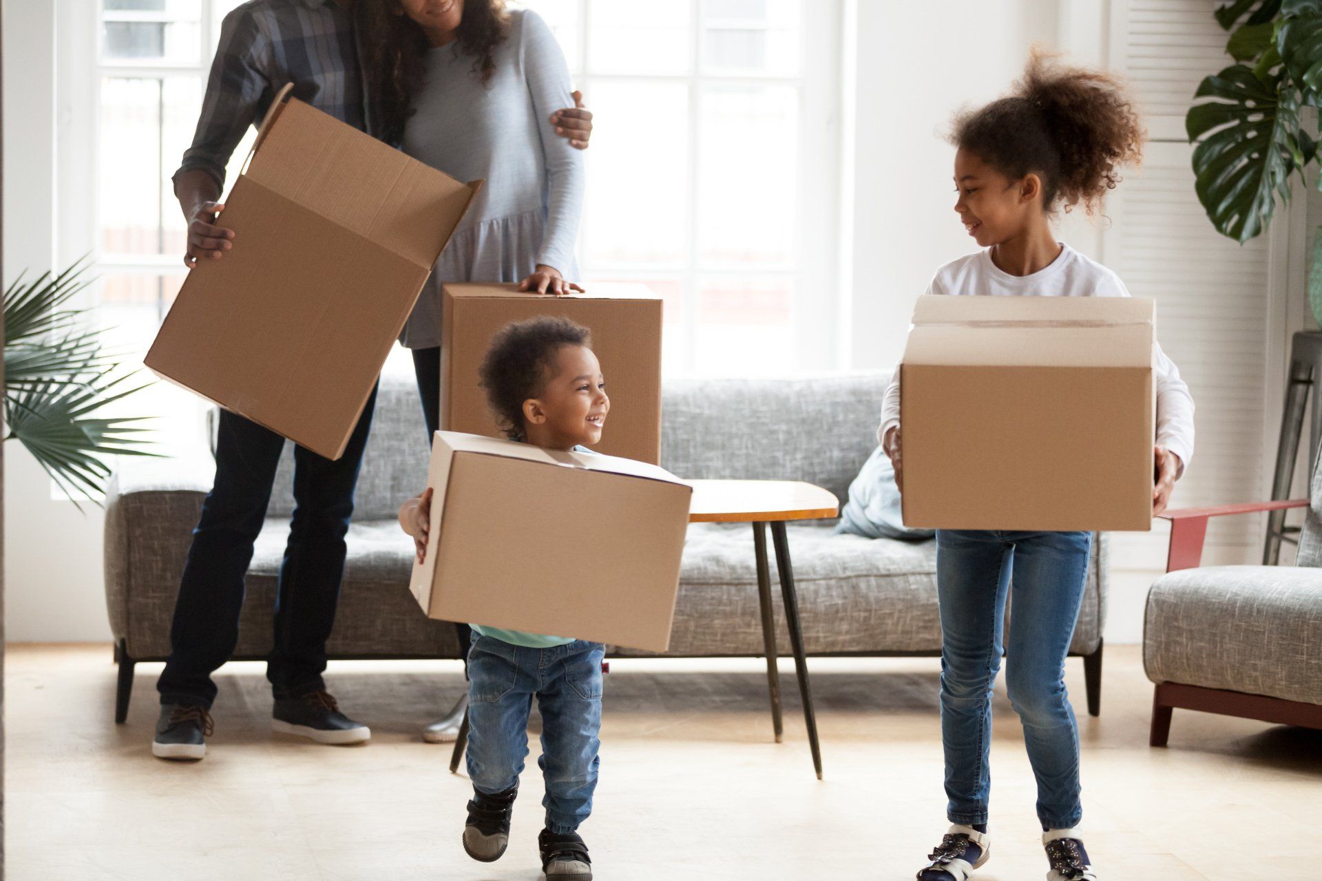 a family is holding cardboard boxes in a living room .